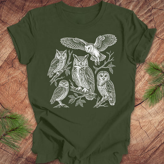 Green t-shirt with white owl line-art illustrations on a wooden surface