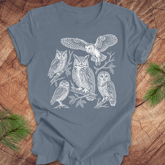 Blue t-shirt with white owl line-art illustrations on a wooden surface
