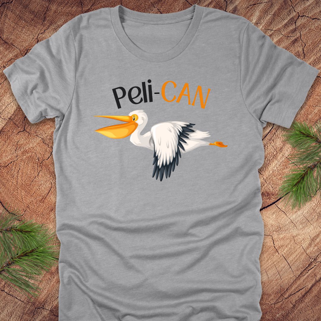 Gray t-shirt with a pelican graphic and 'Peli-CAN' text on a wooden surface.