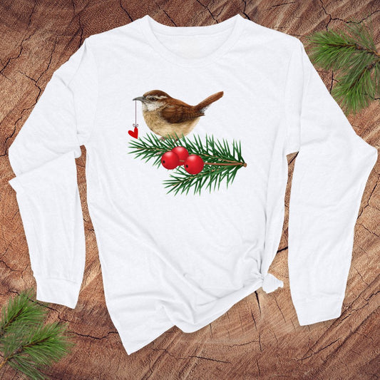 White long-sleeve shirt with a Christmas-themed design featuring a bird, berries, and pine branches on a wooden surface.