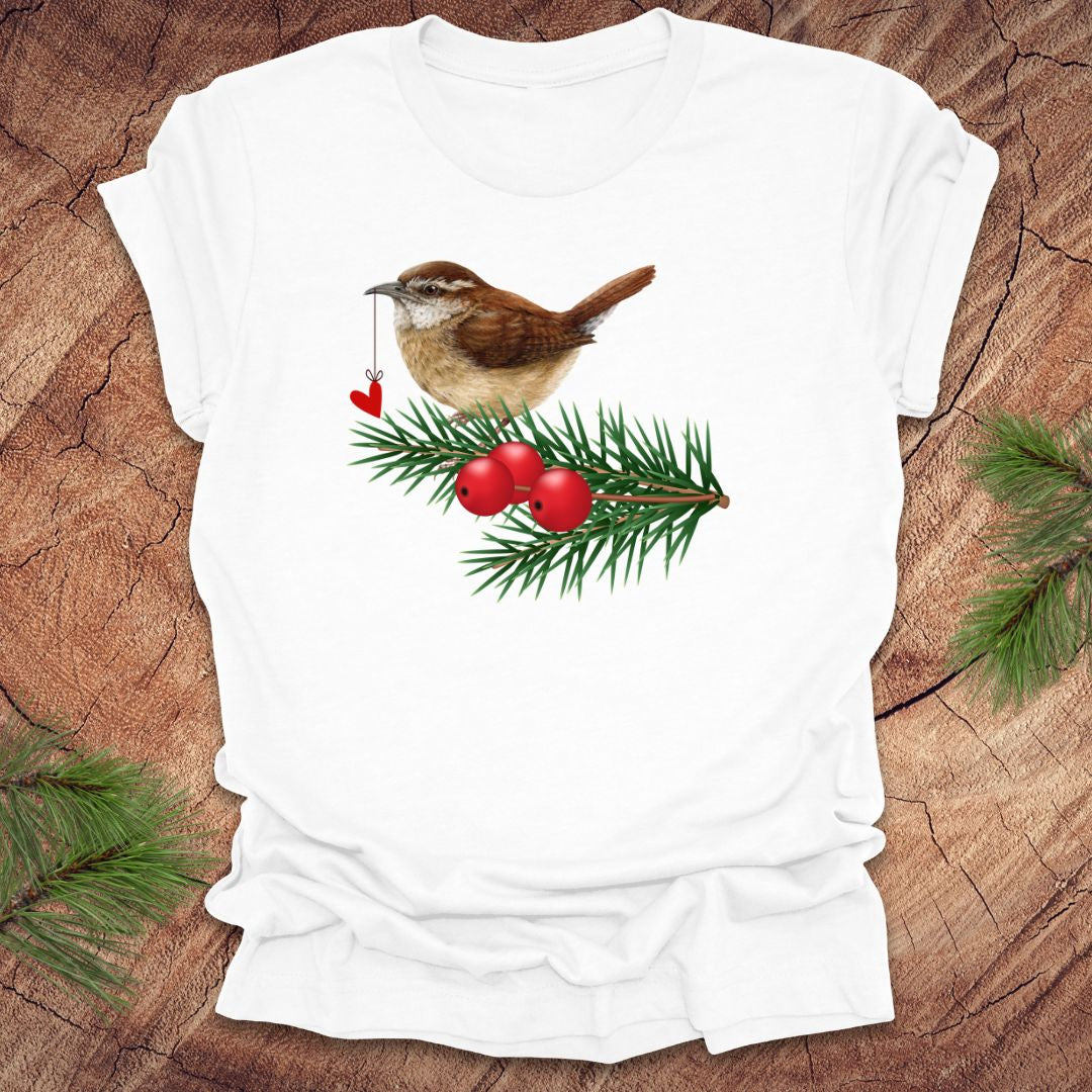 White t-shirt with a wren bird holding a heart on a string and holly design on a wooden surface