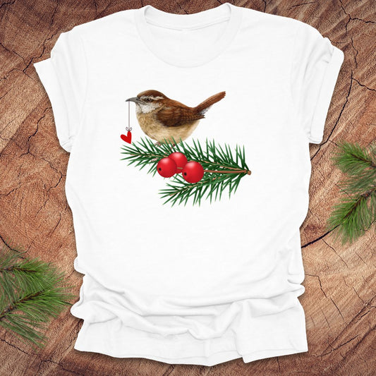 White t-shirt with a wren bird holding a heart on a string and holly design on a wooden surface