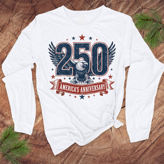 White long-sleeve shirt with '250 America's Anniversary' design on a wooden surface.