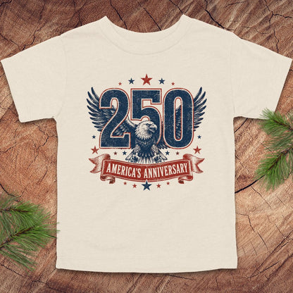 Beige t-shirt with '250 America's Anniversary' design on a wooden surface