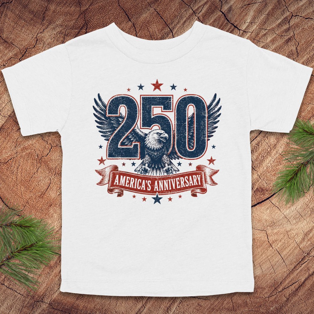 White t-shirt with '250 America's Anniversary' design featuring an eagle on a wooden surface.