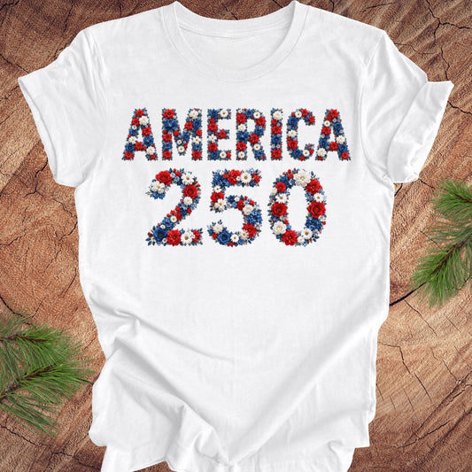 White t-shirt with 'AMERICA 250' design featuring flowers on a wooden surface.