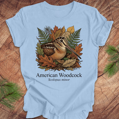Light blue t-shirt with American Woodcock design on a wooden surface