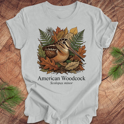 Gray t-shirt with American Woodcock design on a wooden surface