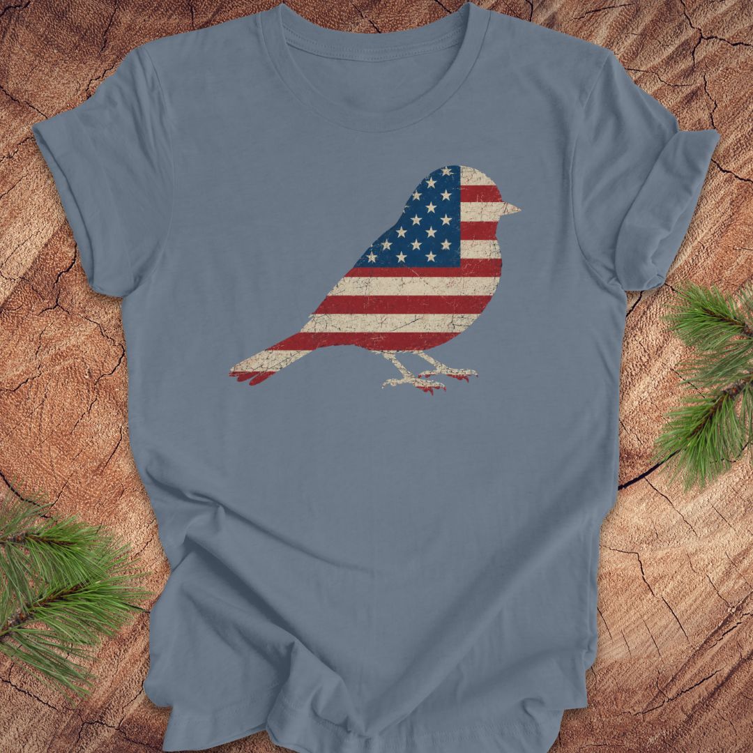Blue t-shirt with a bird-shaped American flag design on a wooden surface.