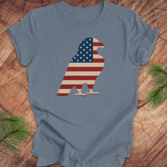 Blue t-shirt with an eagle silhouette in American flag design on a wooden surface.