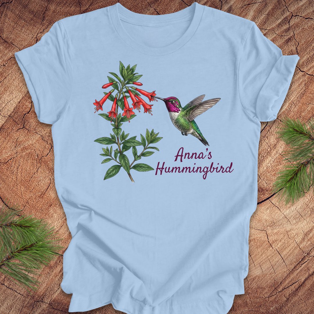 Light blue t-shirt with Anna's Hummingbird design on a wooden surface