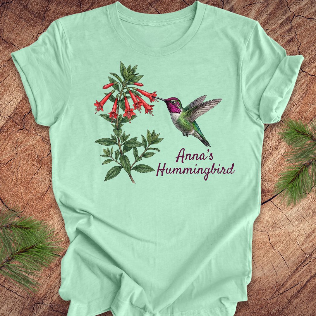 Mint green t-shirt with Anna's Hummingbird design on a wooden surface