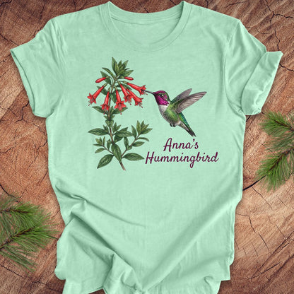 Mint green t-shirt with Anna's Hummingbird design on a wooden surface