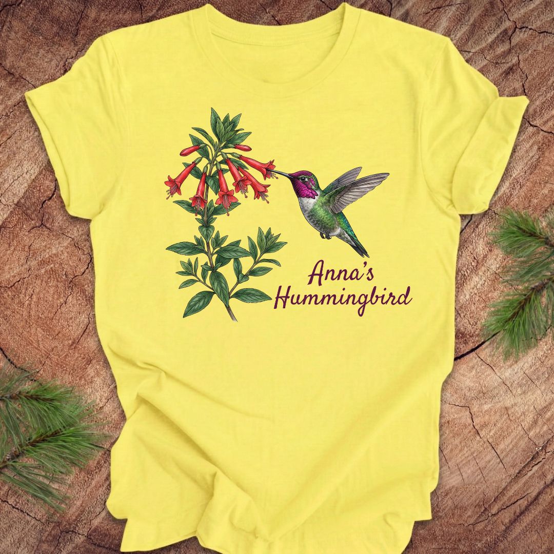 Yellow t-shirt with Anna's Hummingbird design on a wooden surface