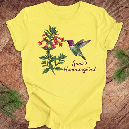 Yellow t-shirt with Anna's Hummingbird design on a wooden surface