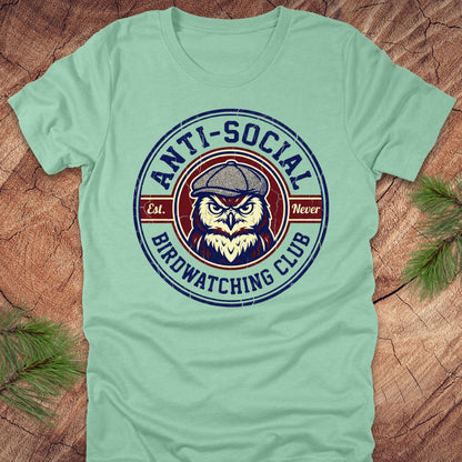 Light green t-shirt with 'Anti-Social Birdwatching Club' graphic on a wooden surface.
