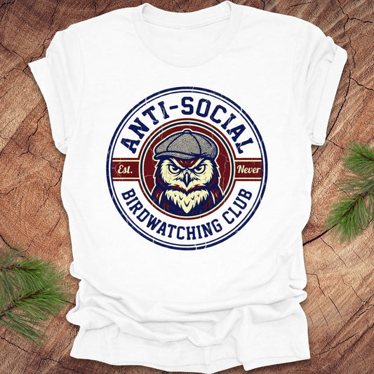 White t-shirt with 'Anti-Social Birdwatching Club' graphic on a wooden surface with greenery.