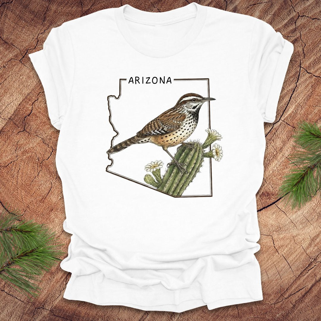 White t-shirt with Arizona state outline with cactus wren and cactus flower design on a wooden surface