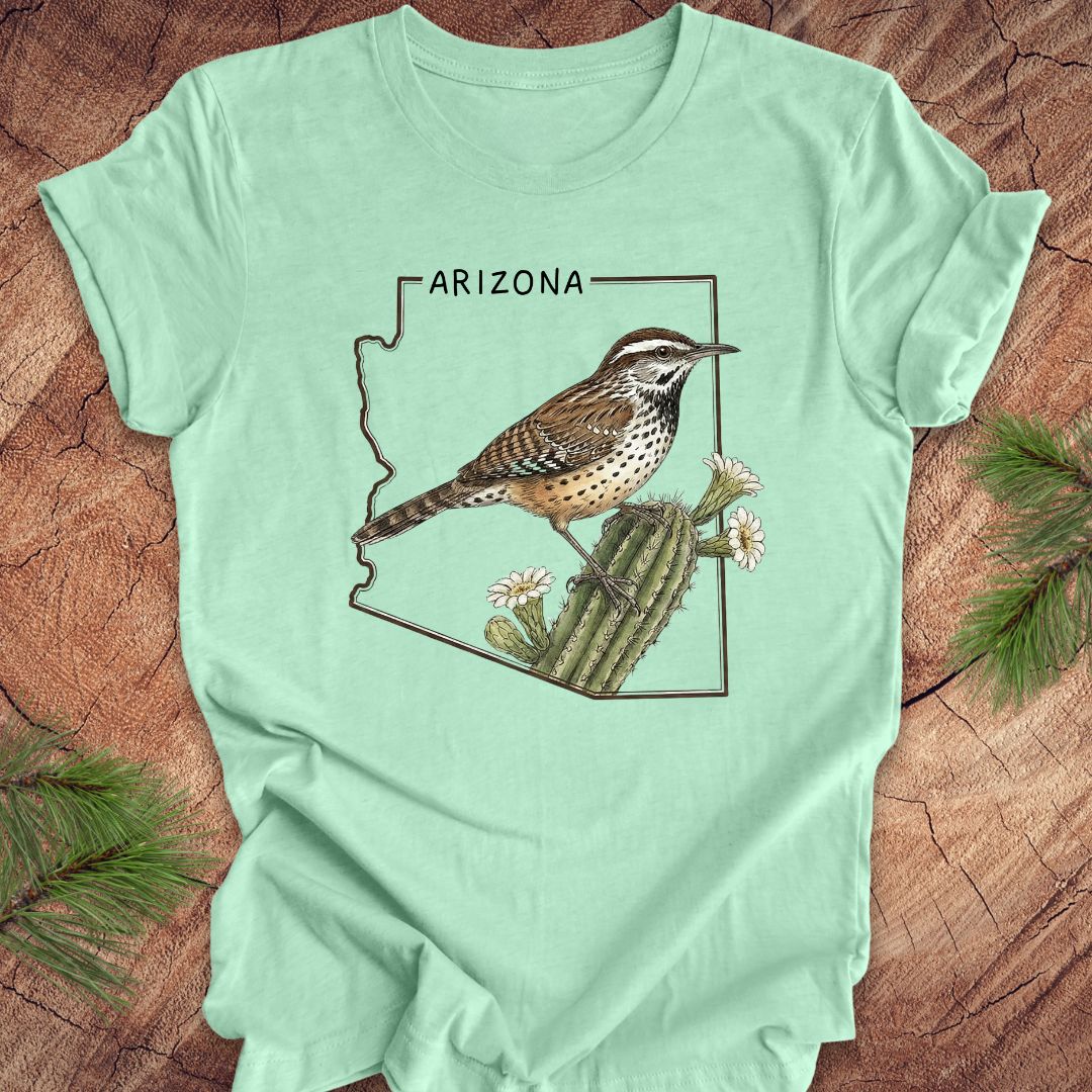 Mint green t-shirt with Arizona state outline with cactus wren and cactus flower design on a wooden surface
