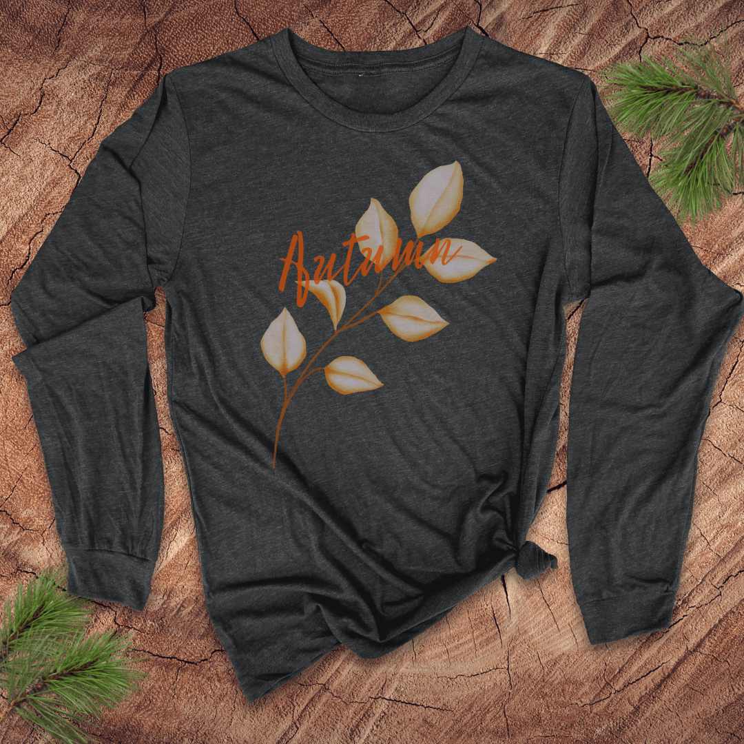grey long sleeve tshirt with the word autumn and a long stemmed leaf, on a wood background with pine leaves