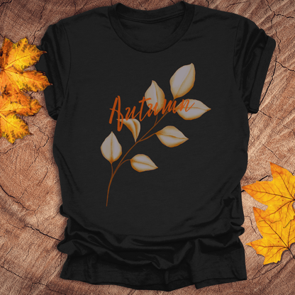 Black t-shirt with 'Autumn' and leaf design on a wooden surface with fall leaves.
