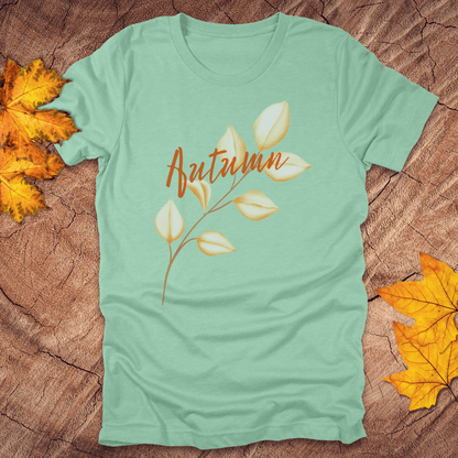 Mint green t-shirt with 'Autumn' design on a wooden surface with fall leaves.