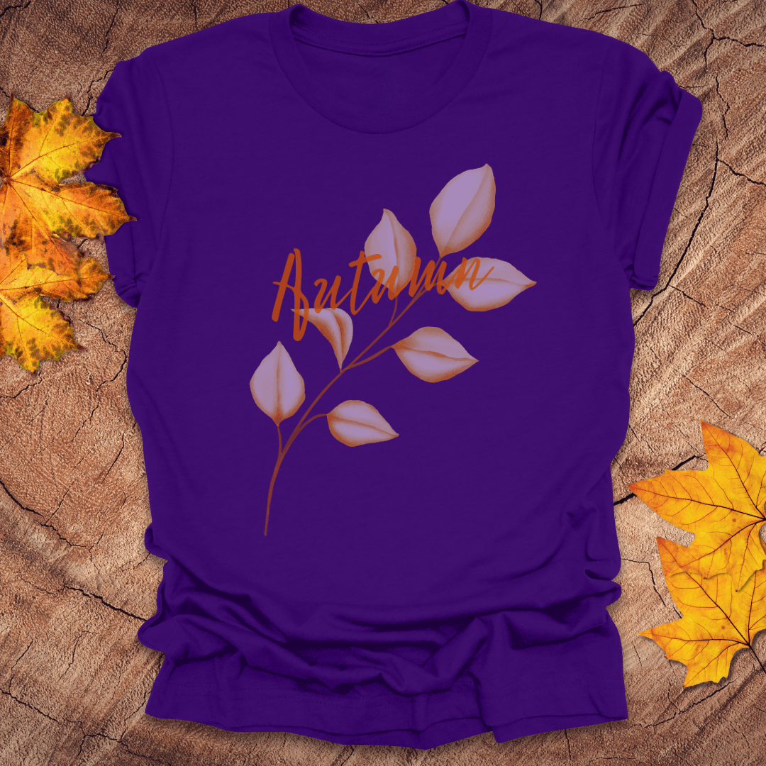 Purple t-shirt with 'Autumn' and leaf design on a wooden surface with fall leaves.