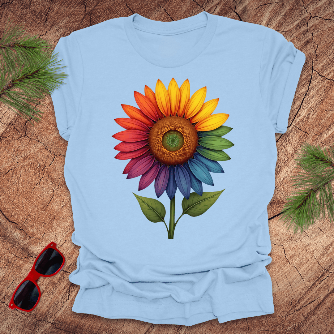 Baby blue tshirt with a bold rainbow sunflower graphic on a wood background.