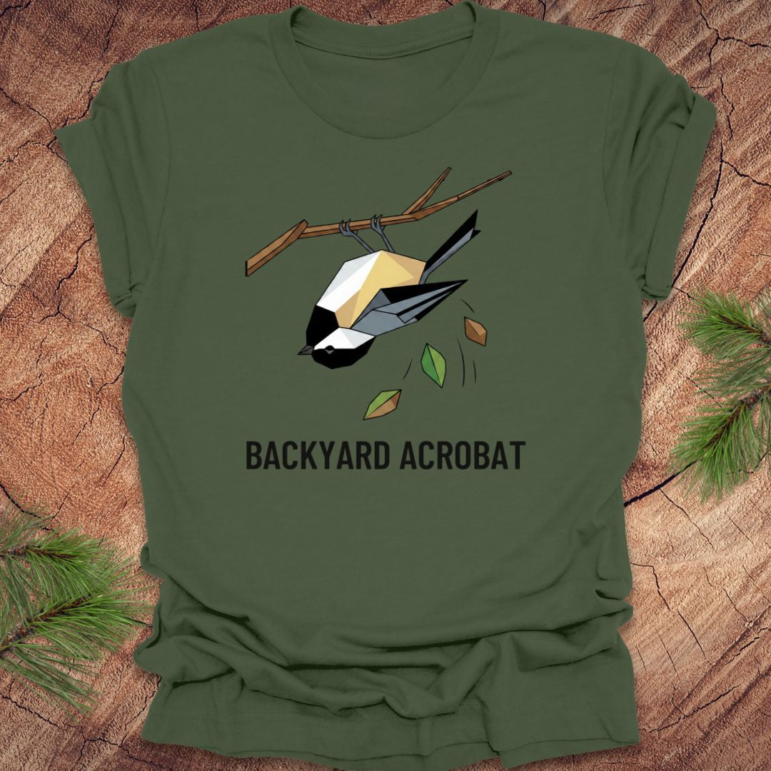 Green t-shirt with a chickadee graphic and 'Backyard Acrobat' text on a wooden surface.