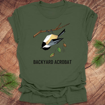 Green t-shirt with a chickadee graphic and 'Backyard Acrobat' text on a wooden surface.