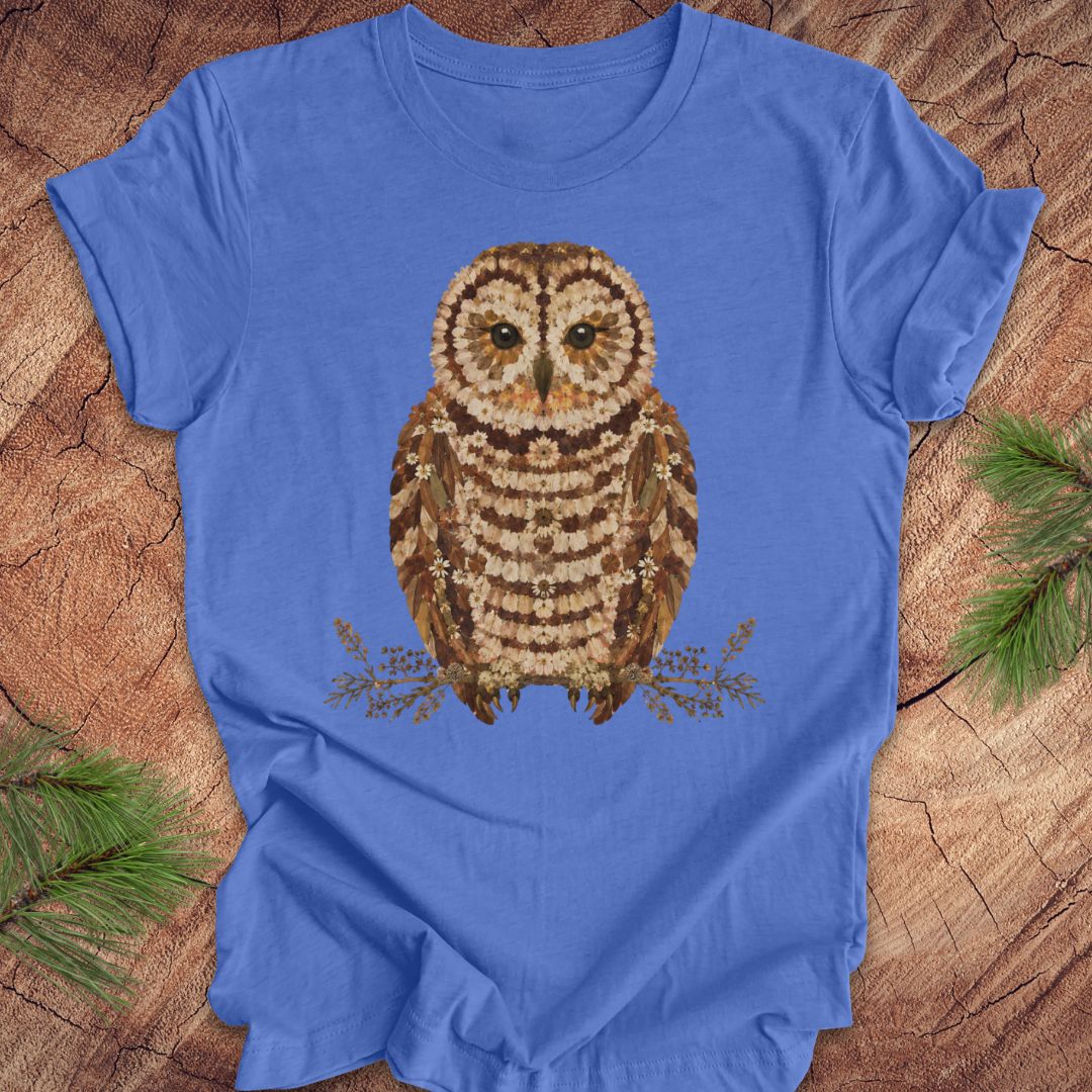 Blue t-shirt with an owl and flower design on a wooden surface