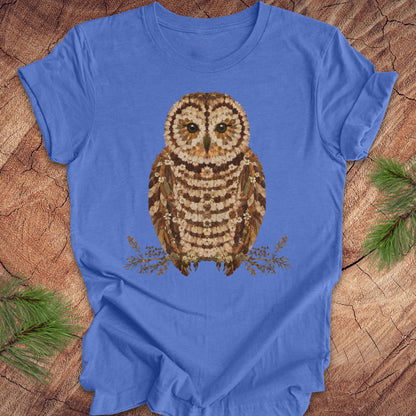 Blue t-shirt with an owl and flower design on a wooden surface