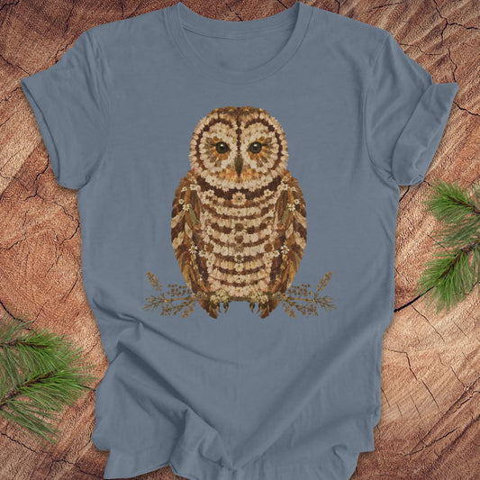 Blue t-shirt with an owl and flower design on a wooden surface