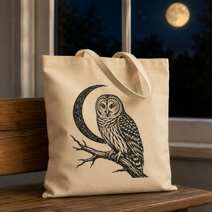A natural canvas tote bag with a black line art illustration of an owl perched on a crescent moon, sitting on a wooden bench in front of a window at night with a full moon visible.