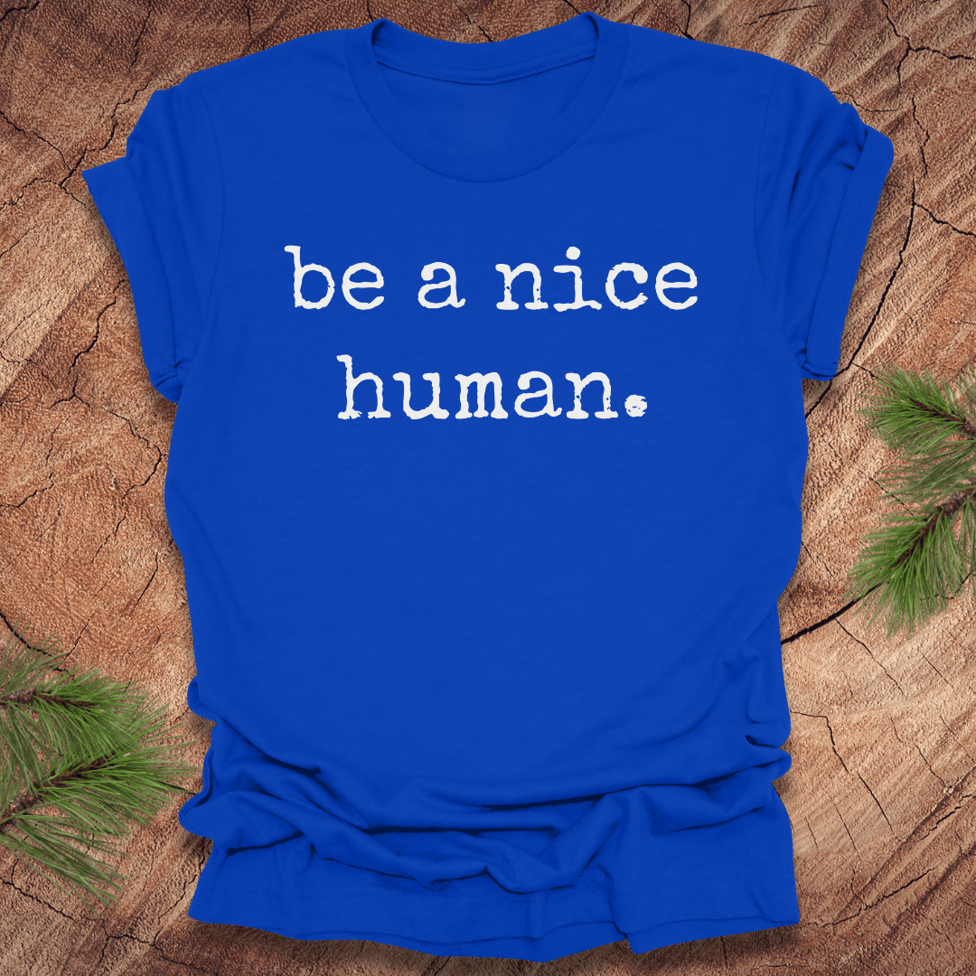 Royal blue t-shirt with 'be a nice human' text on a wooden surface