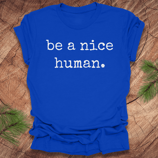 Royal blue t-shirt with 'be a nice human' text on a wooden surface