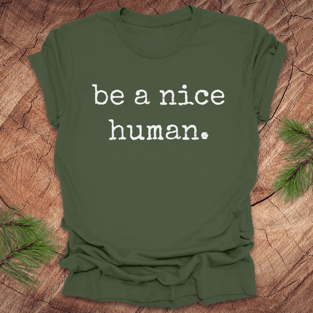 Green t-shirt with 'be a nice human' text on a wooden surface