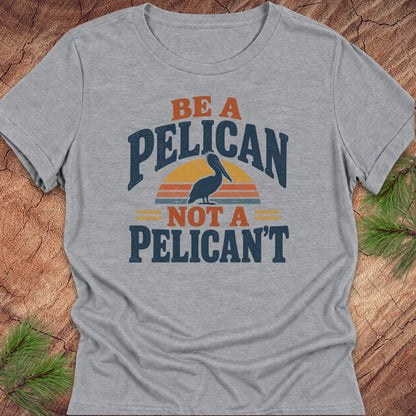 Athletic heather gray women's relaxed t-shirt with a Brown Pelican silhouette on a retro striped sunset and the words BE A PELICAN NOT A PELICAN'T, laid flat on a rustic wood background with pine branches.