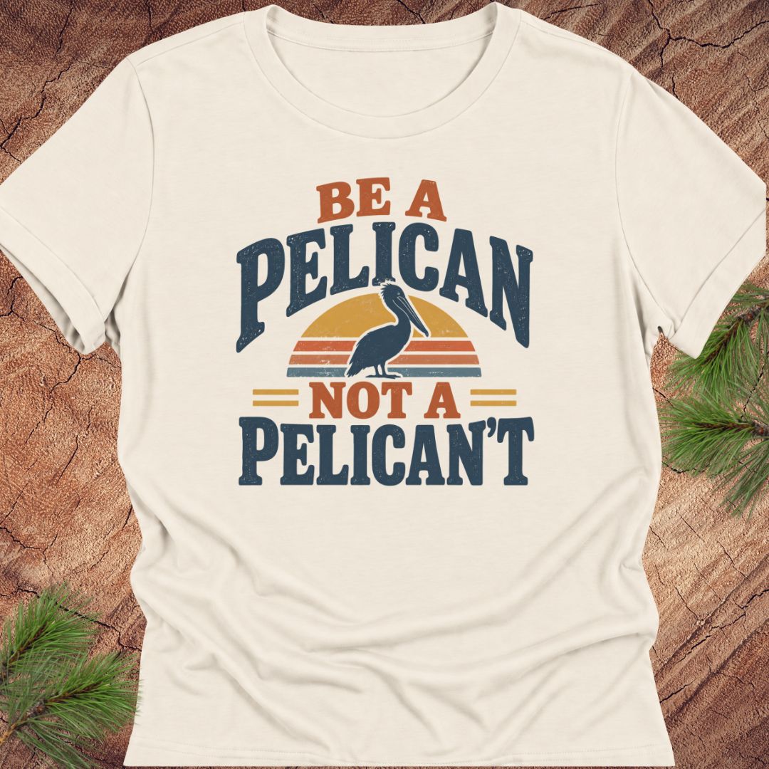 Natural cream women's relaxed t-shirt with a Brown Pelican silhouette on a retro striped sunset and the words BE A PELICAN NOT A PELICAN'T, laid flat on a rustic wood background with pine branches.