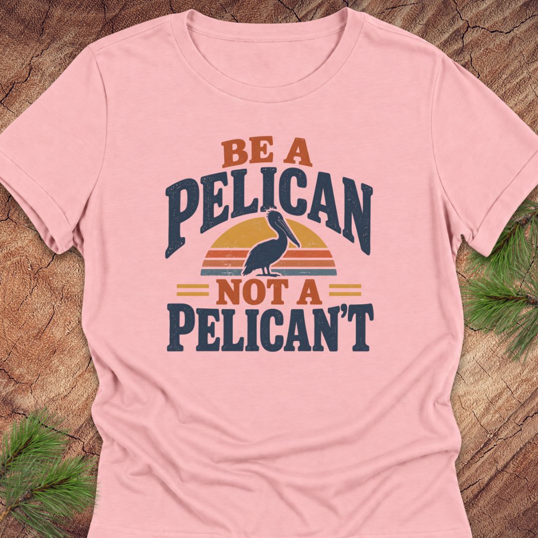 Pink women's relaxed t-shirt with a Brown Pelican silhouette on a retro striped sunset and the words BE A PELICAN NOT A PELICAN'T, laid flat on a rustic wood background with pine branches.