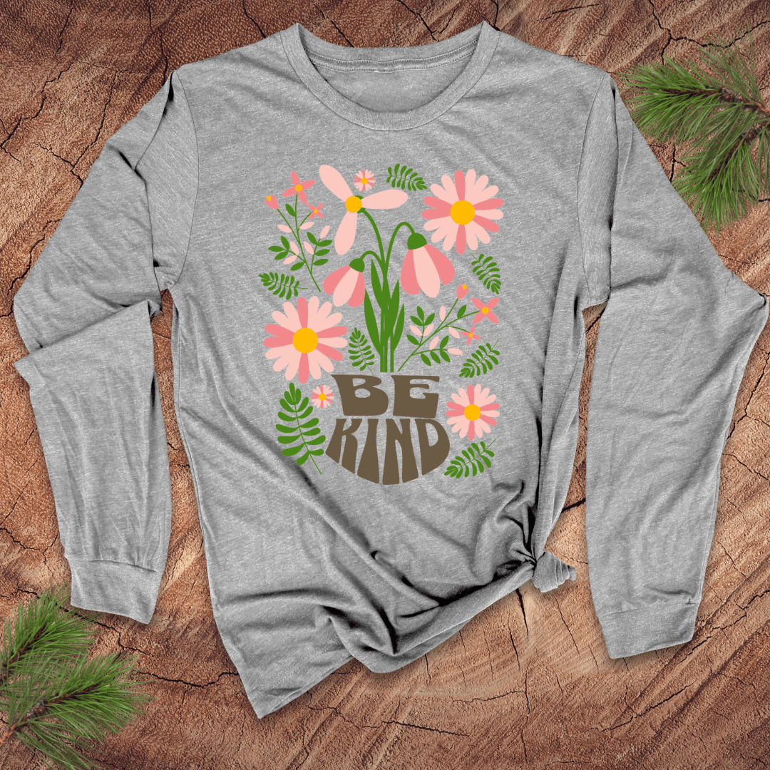 Gray long-sleeve shirt with floral design and 'Be Kind' text on a wooden surface