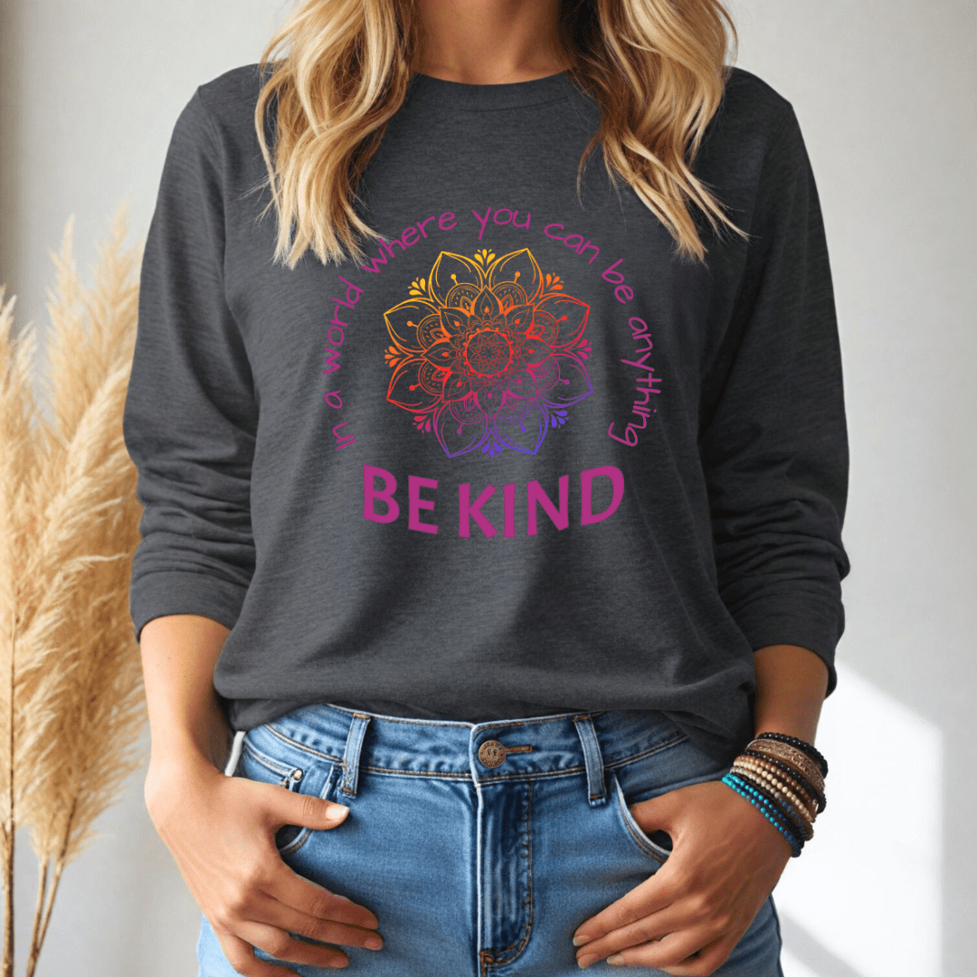 Person wearing a dark gray long sleeve tshirt with a colorful mandala design and text, standing against a neutral background.