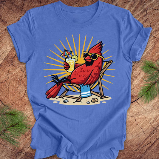 Blue t-shirt with a red cardinal wearing sunglasses and holding a drink on a wooden surface.