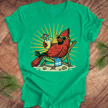 Green t-shirt with a cardinal wearing sunglasses and holding a drink on a wooden surface