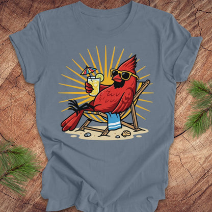 Blue t-shirt with a red cardinal wearing sunglasses and holding a drink on a wooden surface.