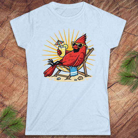 Blue t-shirt with a cardinal design sitting in a chair, drinking a cocktail, on a wooden surface.