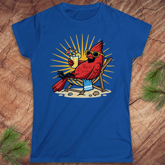 Blue t-shirt with a cardinal design sitting in a chair, drinking a beer, on a wooden surface.