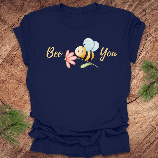 Navy blue tshirt with a cute bee and the text, "bee you" on a wooden background