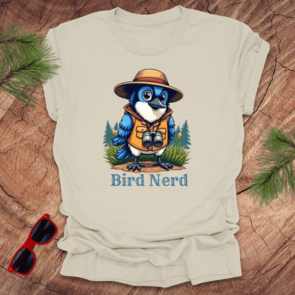 Beige t-shirt with an animated blue jay in birdwatching gear with "bird nerd" text on a wood background.