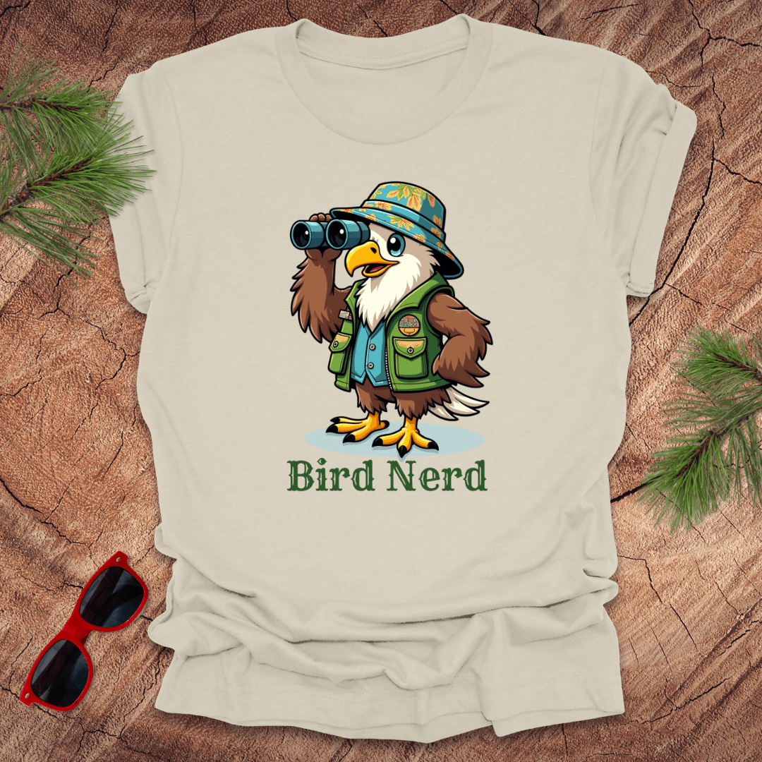 Beige t-shirt with an animated eagle in birdwatching gear with "bird nerd" text on a wood background.